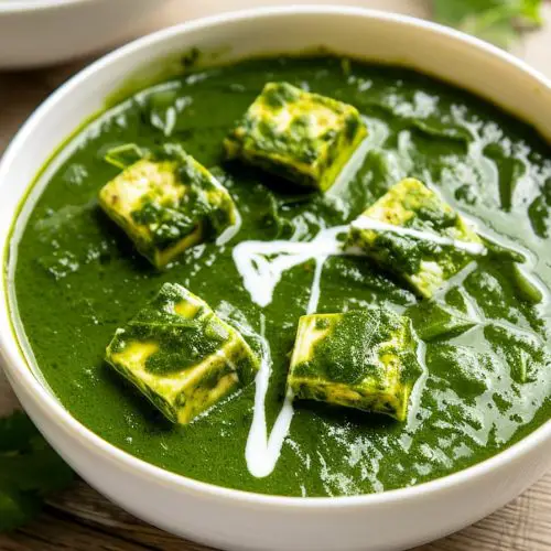 Palak Paneer Curry Recipe Served on a white bowl garnished with cream and cilantro leaves