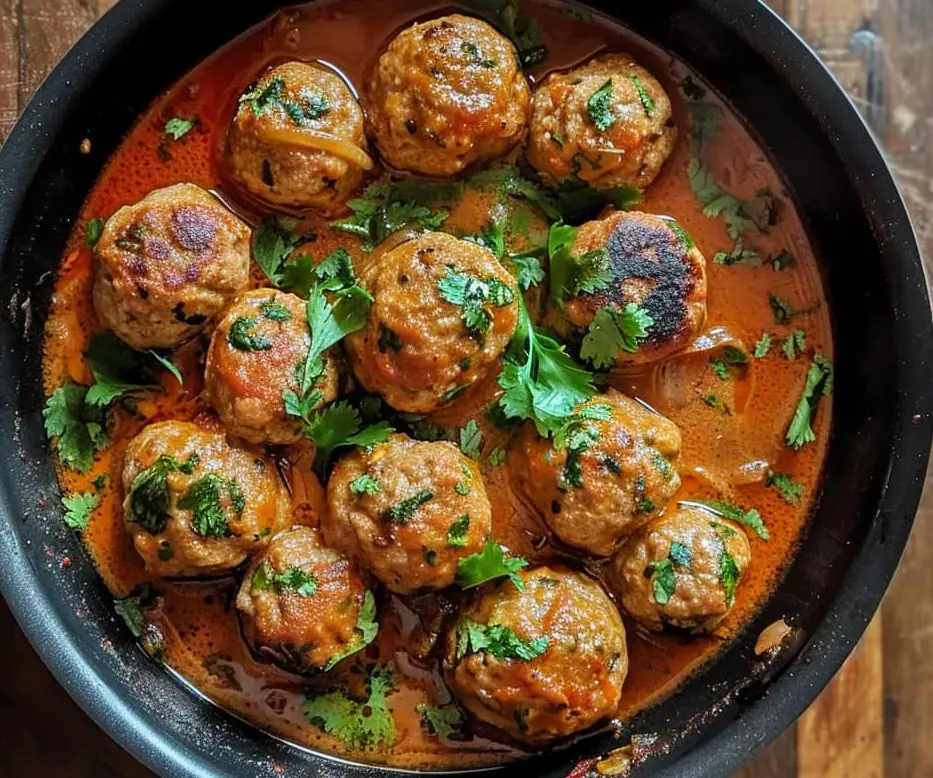 meatballs put inside the curry base in a black pan