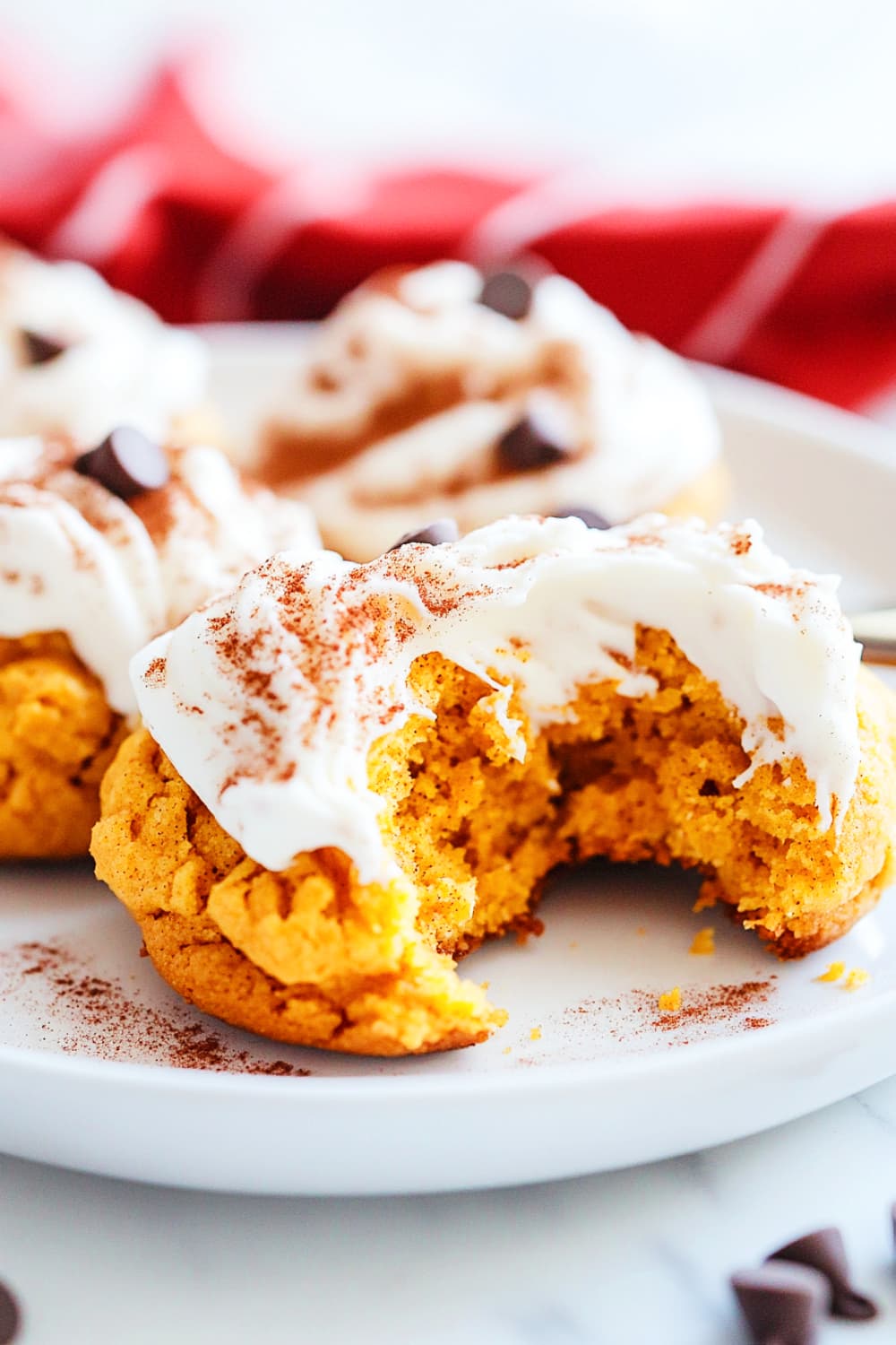 Snickerdoodle pumpkin cookies with cheese cream frosting, choco chips with a bite taken