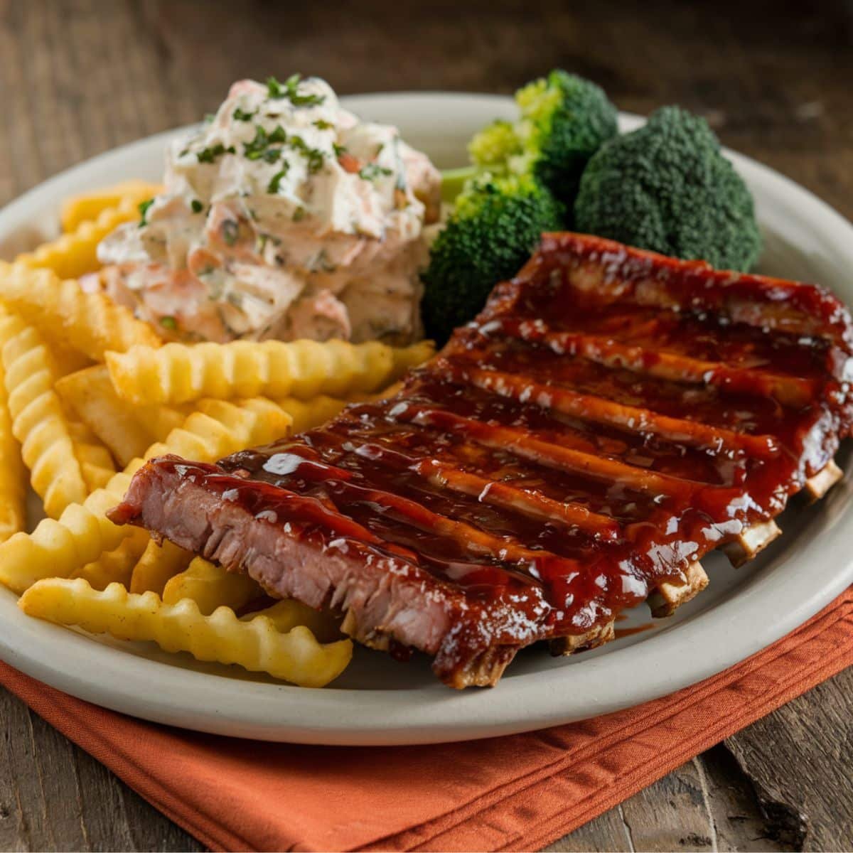 Juicy Boneless Beef Ribs glazed with barbecue sauce, served with crinkle-cut fries, creamy coleslaw, and steamed broccoli on a rustic plate - perfect for a delicious Boneless Beef Ribs Recipe meal.
