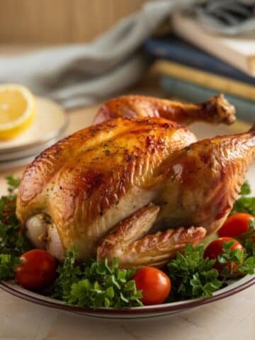 Whole roasted chicken recipe featuring a golden, crispy chicken garnished with fresh parsley and cherry tomatoes, perfect for a classic and flavorful meal.