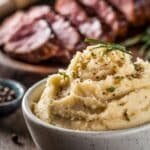Rustic Cowboy Butter Recipe featuring creamy mashed potatoes garnished with fresh herbs and black pepper, served alongside juicy sliced steak in a cozy, rustic setting.