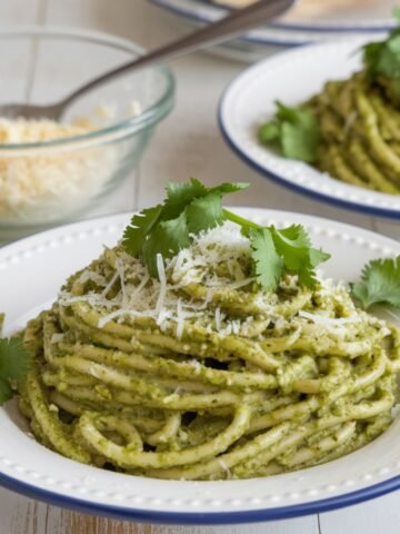Creamy Green Spaghetti Recipe served on a white plate, topped with fresh cilantro and grated cheese. A flavorful and easy-to-make pasta dish with a rich poblano-based green sauce.