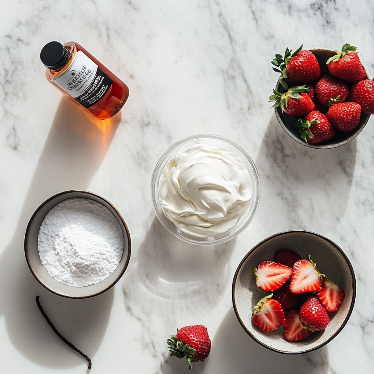 Flat lay of whipped cream, powdered sugar, vanilla extract, and fresh strawberries on a marble counter, prepared for strawberry poke cake topping.