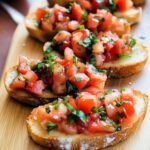 Homemade bruschetta with toasted bread topped with fresh diced tomatoes, basil, garlic, and olive oil on a wooden board.