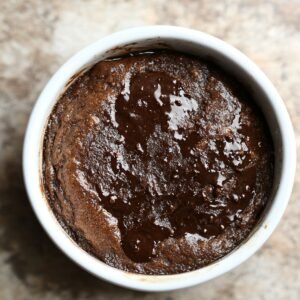 Freshly baked chocolate pudding cake in a white ramekin, with a glossy, molten center and a soft, risen top.