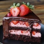 Slice of homemade chocolate strawberry cake with rich layers, fresh strawberries, pink cream filling, and glossy chocolate ganache on top.