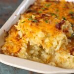 Homemade hashbrown casserole with a golden, cheesy top and creamy potato filling, served in a ceramic baking dish