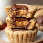 Homemade peanut butter cup cookies, with gooey chocolate and peanut butter centers, cut open to show soft, golden, freshly baked texture.