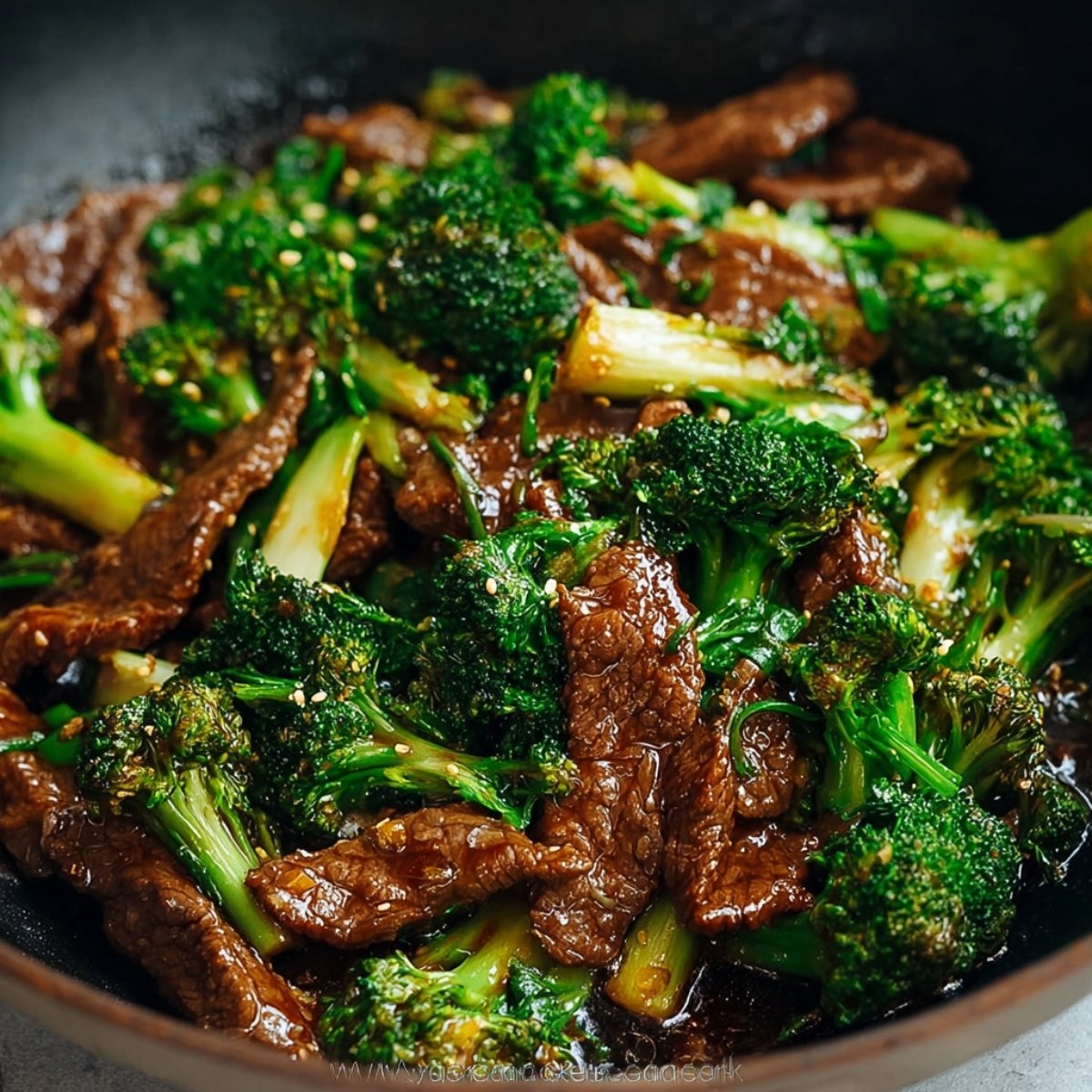 Chinese Beef and Broccoli over white rice in a dark bowl, with tender beef in glossy brown sauce, vibrant broccoli, and green onion garnish, natural light.
