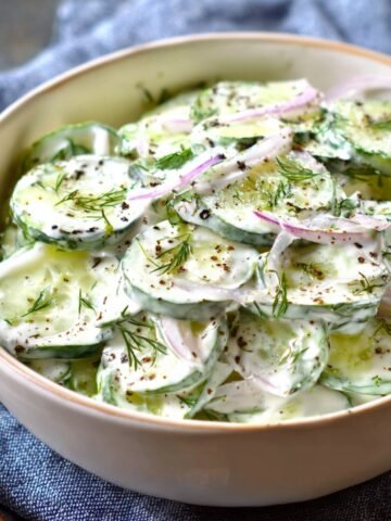 Creamy cucumber salad with red onion, fresh dill, and black pepper.
