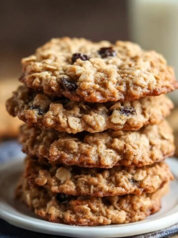 Homemade Quaker Oatmeal Cookie Recipe on a white plate, golden-brown with oats and raisins, crisp edges, soft centers, cozy kitchen feel.