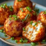 Homemade Rangoon Crab Bombs with green onions, one cut open showing creamy crab filling, served with soy chili dipping sauce on a blue-and-white plate.