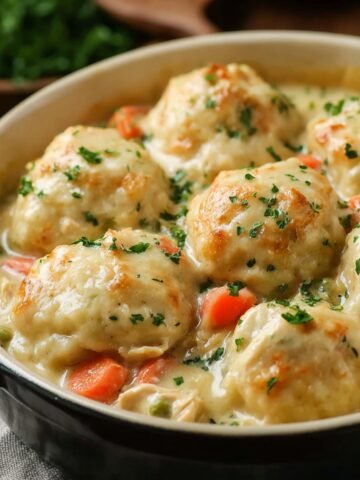 Homemade Bisquick chicken and dumplings in a creamy stew with tender carrots, parsley, and golden dumplings in a farmhouse-style dish.