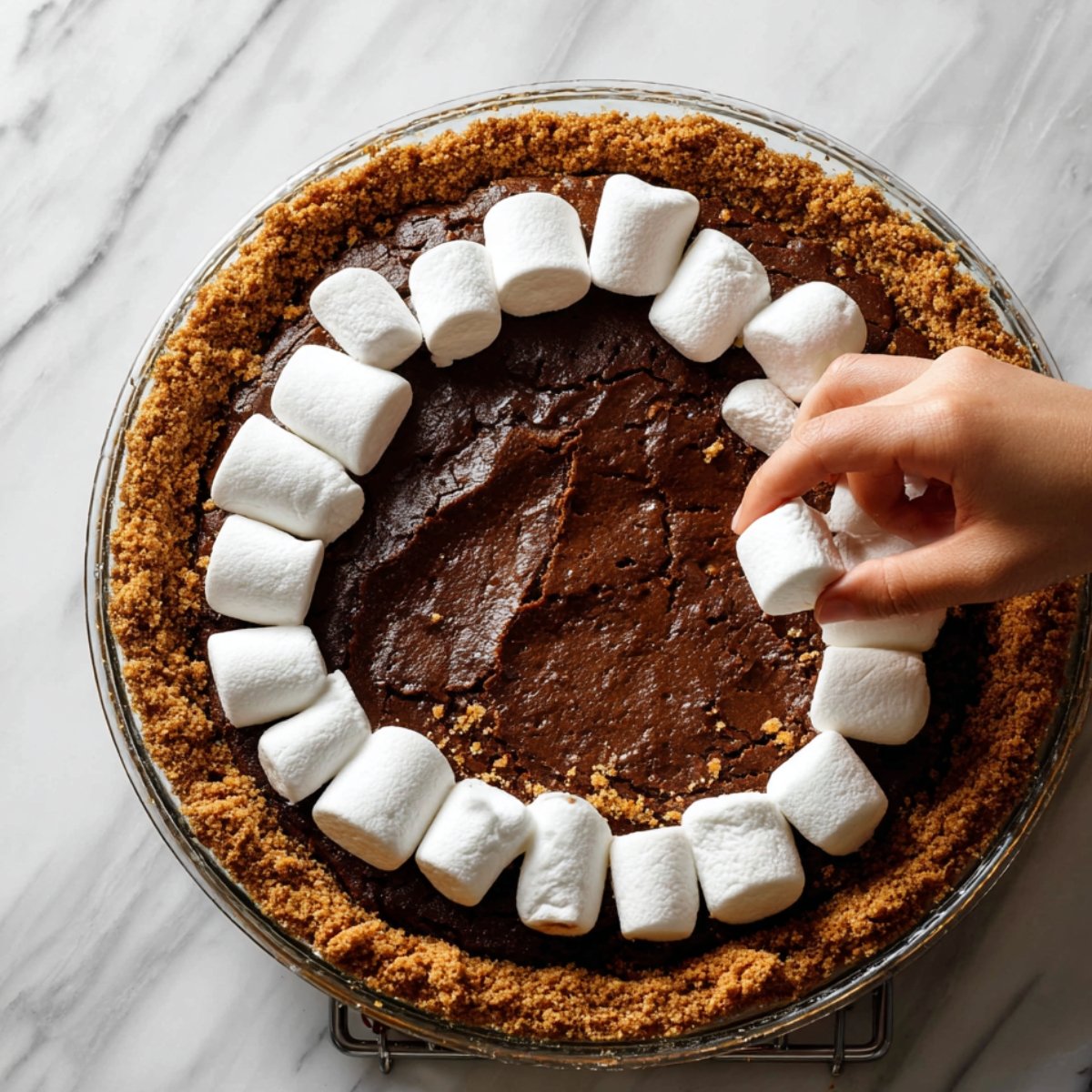 Pull the pie out and arrange your marshmallows across the top, pressing them very gently into the brownie filling so they stick. You want to cover most of the surface.