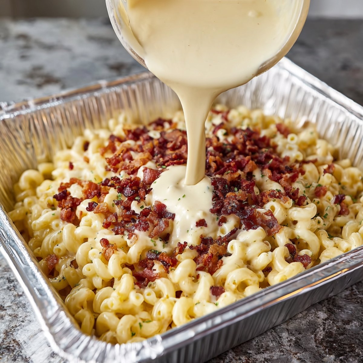 Grab your 9" x 13" foil pan and combine the cooked pasta, crumbled bacon, and all that gorgeous cheese sauce. Stir gently so every piece of pasta gets coated. Sprinkle your reserved cheese on top and add a little extra BBQ seasoning if you're feeling bold.