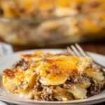 Hamburger Potato Casserole sits on a plate, layered with tender potatoes, browned beef, and golden melted cheese.