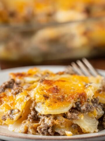 Hamburger Potato Casserole sits on a plate, layered with tender potatoes, browned beef, and golden melted cheese.