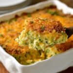 Slice of homemade cheesy zucchini casserole on a plate, showing a golden, crispy breadcrumb topping and tender zucchini filling.