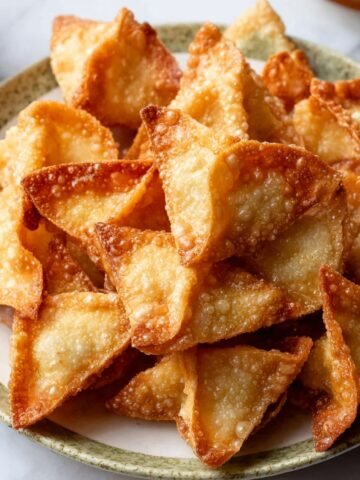 A plate of golden, crispy crab rangoons with perfectly browned edges, arranged neatly.