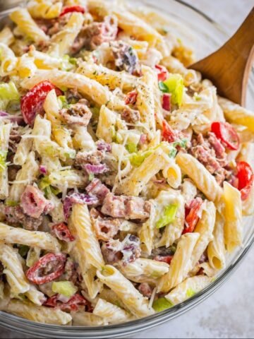 Homemade Italian Grinder Pasta Salad with spiral pasta, tomatoes, lettuce, and bacon, topped with Parmesan and creamy dressing.