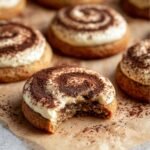 Tiramisu Cookies with a swirl of mascarpone cream and cocoa powder, with a bite taken out.