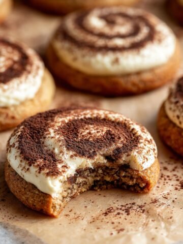 Tiramisu Cookies with a swirl of mascarpone cream and cocoa powder, with a bite taken out.