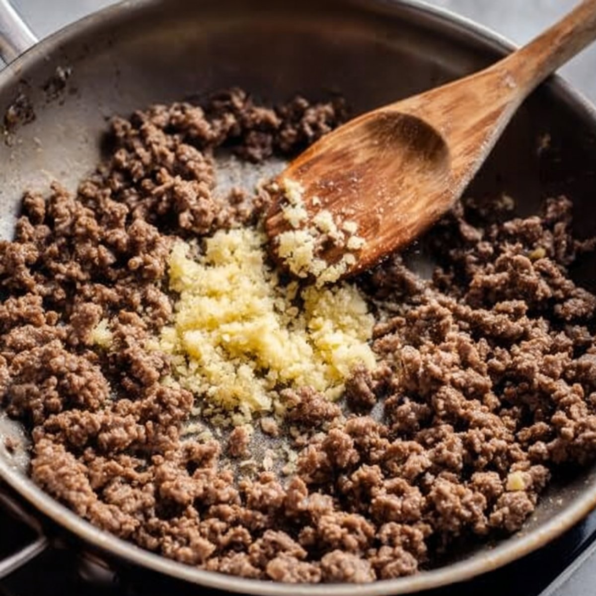 Toss in the minced ginger and garlic, stirring them into the beef. Cook for 2 to 3 minutes until everything smells fragrant and the garlic is just starting to turn golden.