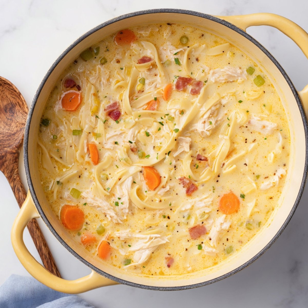 Stir in the uncooked egg noodles and shredded cheddar cheese. Keep the heat on low and cook for 5 to 6 more minutes, stirring now and then, until the noodles are tender and the cheese has melted completely.
