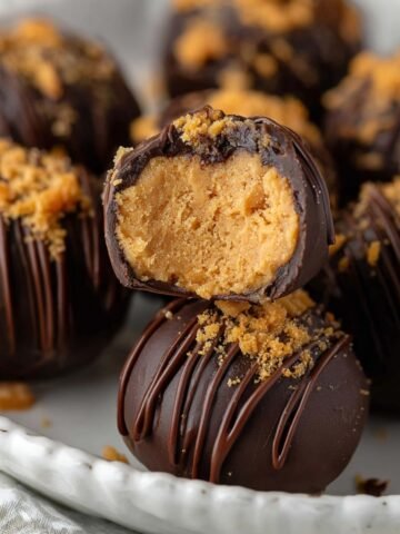 Butterfinger Balls with chocolate drizzle and crushed candy on a plate.