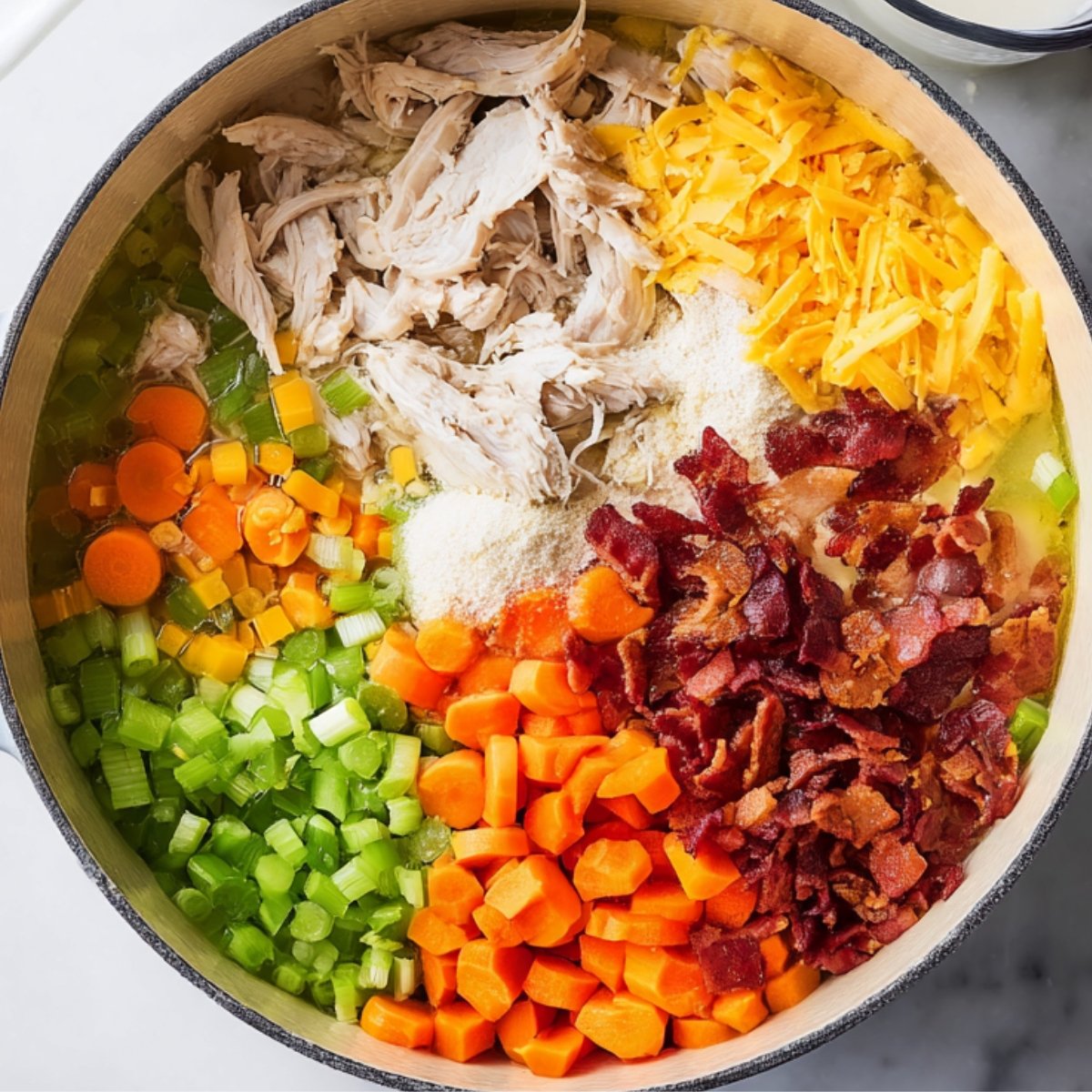 In a large Dutch oven, add the chopped chicken, condensed chicken soup, chicken broth, milk, softened cream cheese, celery, carrots, ranch seasoning mix, and crumbled bacon. Stir everything together so the cream cheese starts to break down and blend into the liquid.