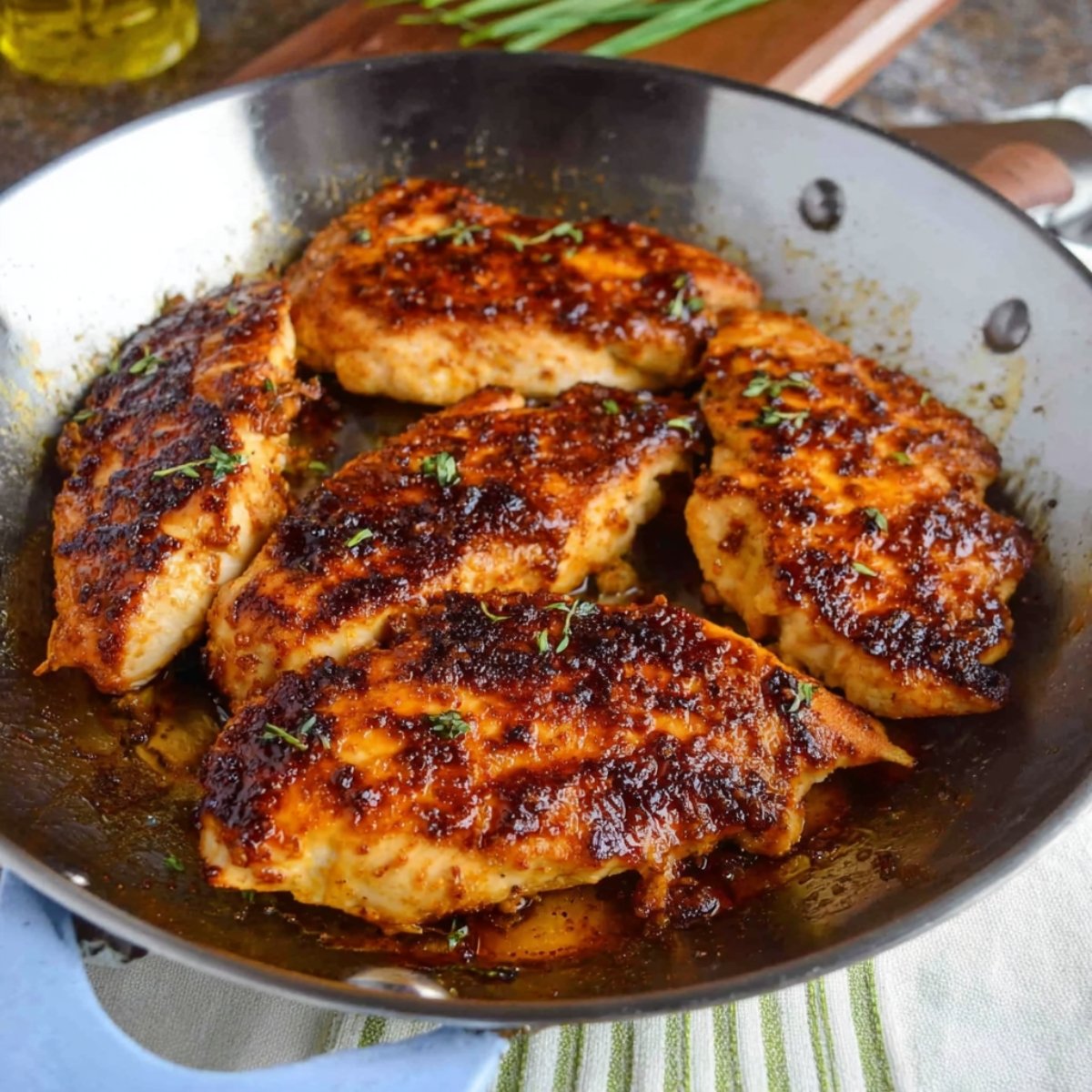 Pan-seared chicken breasts cooking to a golden brown with a crispy, caramelized crust in a frying pan.