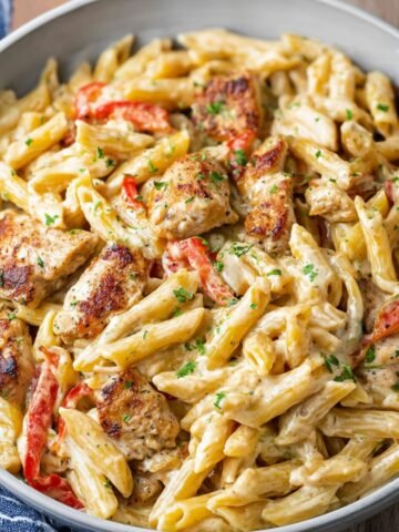 Creamy Cajun chicken pasta with penne, bell peppers, and parsley served in a bowl.