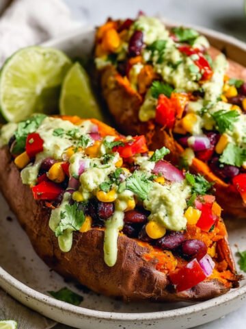 Healthy Mexican Stuffed Sweet Potatoes filled with black beans, corn, peppers, and drizzled with creamy avocado sauce in a rustic bowl.