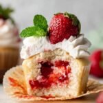 Homemade Strawberry Shortcake Cupcakes filled with strawberry compote and topped with whipped cream, strawberry, and mint