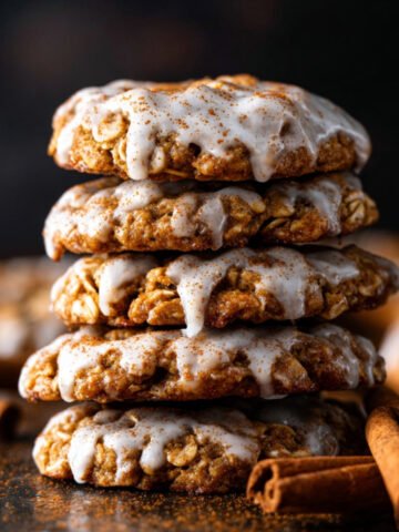 Stack of Iced Gingerbread Oatmeal Cookies drizzled with cinnamon glaze and sprinkled with spice.