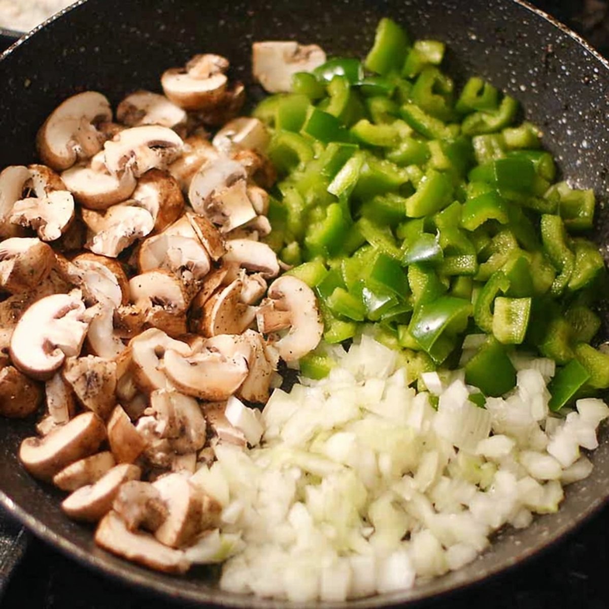 Sautéed vegetables, including onions, green peppers, and mushrooms, in a skillet.