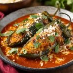 Two delicious Chile Relleno served with tomato sauce, garnished with cilantro and cheese.