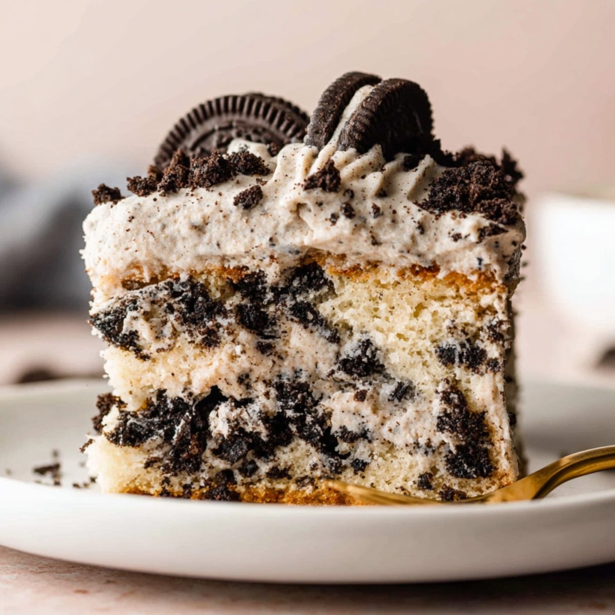 A close-up image of a slice of Cookies and Cream Cake topped with crushed Oreo cookies and creamy frosting.