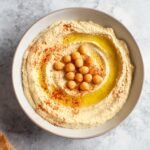 Freshly made Homemade Hummus served in a bowl, garnished with chickpeas, a drizzle of olive oil, and a sprinkle of paprika.