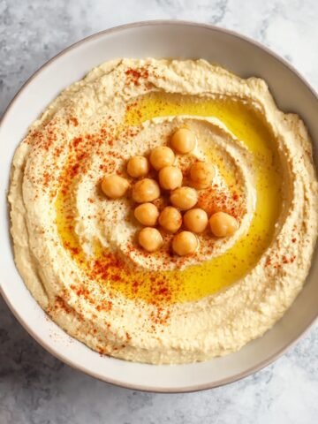 Freshly made Homemade Hummus served in a bowl, garnished with chickpeas, a drizzle of olive oil, and a sprinkle of paprika.