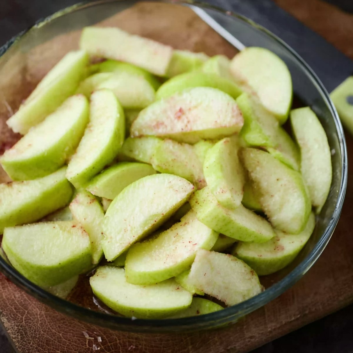 Apple slices in a glass bowl with cinnamon sprinkled on top