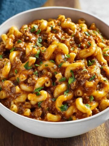 A comforting bowl of One Pot Chili Mac, featuring elbow macaroni mixed with a savory beef and tomato sauce, garnished with fresh parsley.