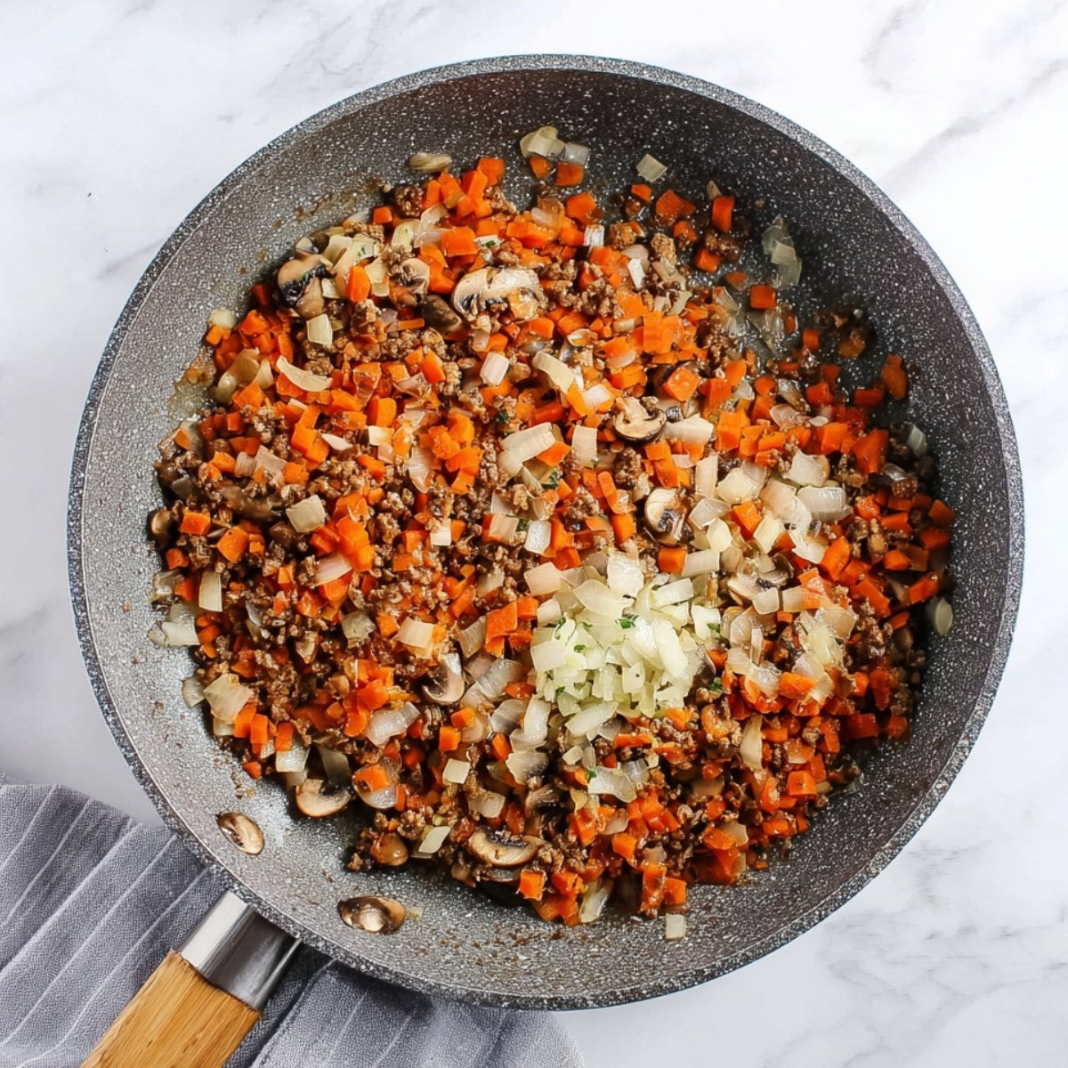 Sautéed carrots, mushrooms, and onions in a pan, ready to be added to the lentil loaf mixture.
