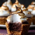 S'mores Brownie Cupcakes with a perfectly toasted meringue topping, revealing the fudgy, chocolate-filled interior and graham cracker crust.