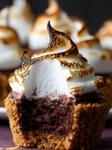 S'mores Brownie Cupcakes with a perfectly toasted meringue topping, revealing the fudgy, chocolate-filled interior and graham cracker crust.