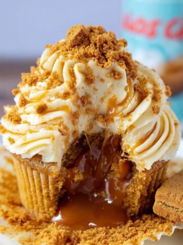 A Biscoff Cupcakes topped with creamy frosting and crumbled Biscoff cookies, revealing a gooey Biscoff filling inside, creating a delicious treat.