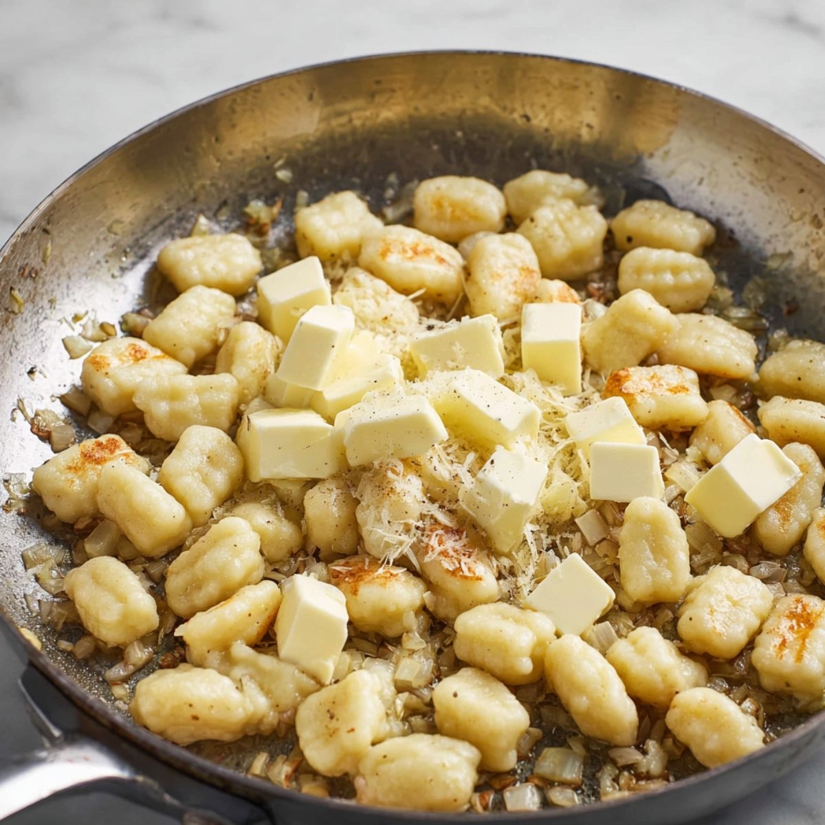 Golden, crispy gnocchi pieces browning in a skillet, coated with a rich sauce and surrounded by sautéed spinach, ready to be served.