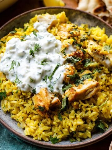 A serving of Chicken Tzatziki and Rice topped with perfectly cooked chicken pieces, fresh herbs, and a generous dollop of tzatziki sauce.